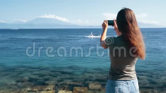 女孩旅行者的后侧视角在手机上拍摄视频如船漂浮慢动作视频的预览图