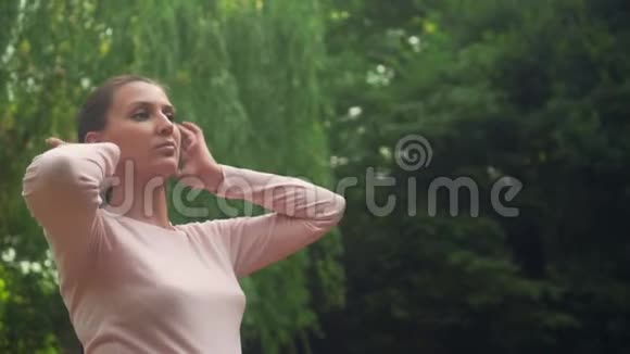 公园里的一个怀孕的女孩在绿柳的背景下平静的女孩抚摸她的头发遮住她的眼睛不受乐趣视频的预览图