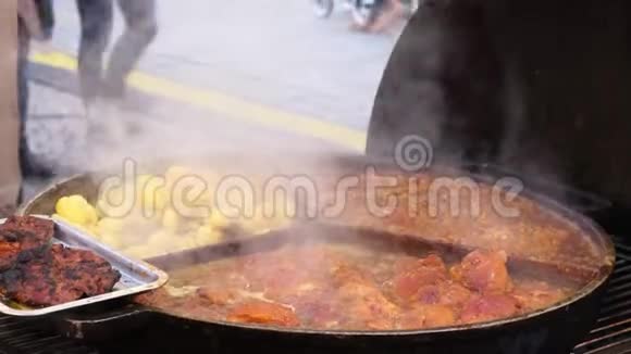 在户外咖啡馆的一个大圆锅上炸鲜肉和土豆在集市上招待饥饿的游客视频的预览图