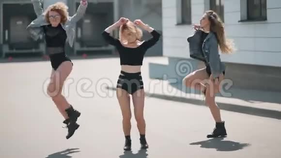 不同的三个女孩朋友在城市里穿着潮流牛仔裤享受乐趣和自由舞蹈视频的预览图
