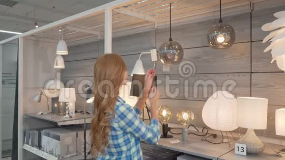 一位在家具店选择灯具的女性顾客的后视镜视频的预览图