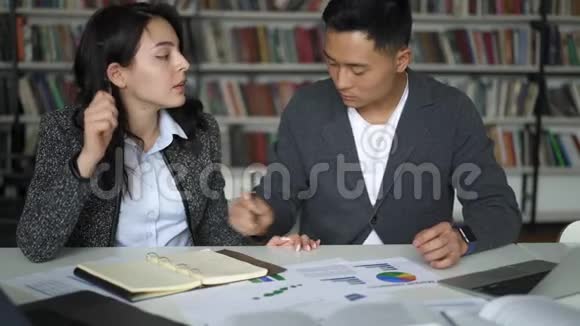 亚洲年轻夫妇在图书馆讨论项目视频的预览图
