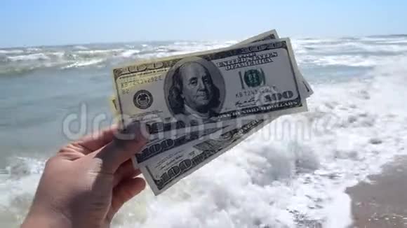 女孩在海浪的背景下持有300美元的钞票视频的预览图