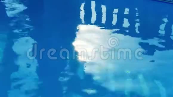 在阳光明媚的日子里游泳池里纯净的蓝色水有着女孩轮廓的光反射塞浦路斯视频的预览图