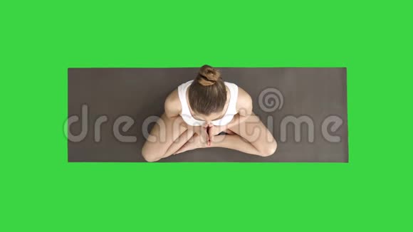美丽的女人在莲花中练习瑜伽姿势伸展手在头上靠在一边靠在绿色上视频的预览图