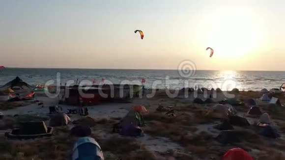 在海滩露营人们在海上玩风筝日落空中射击视频的预览图