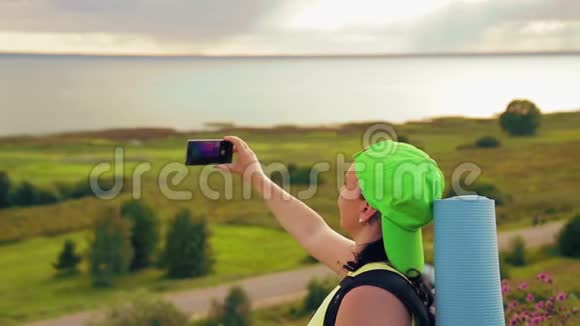 女游客在山上背着背包和望远镜在电话上拍照视频的预览图