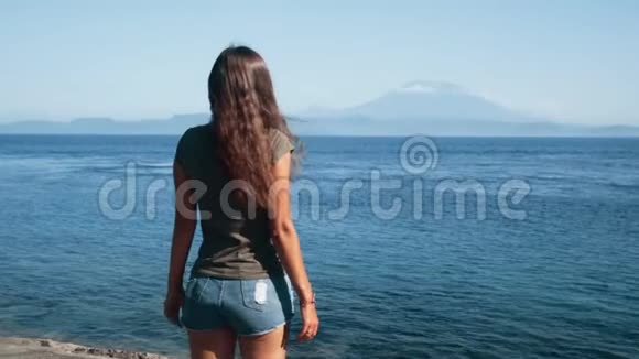 女旅行者张开双臂欣赏海洋高山慢动作视频的预览图