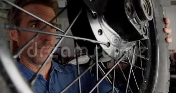 男机修工检查修理车库4k的摩托车轮视频的预览图