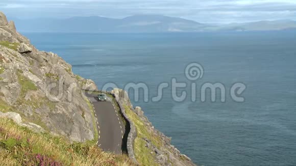 一辆车在海边悬崖上的一条狭窄的路上视频的预览图