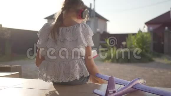 背景一个戴着耳机的可爱小女孩在看书小飞机躺在门廊上孩子视频的预览图