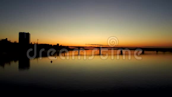 在大城市日落时桥在一条宽阔的河流上的黑暗空中景色日落反映在water4kCopy上视频的预览图