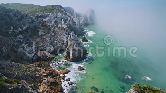 4K岩石在大西洋海岸线的晨雾中背景是葡萄牙辛特拉的卡波达罗卡灯塔视频的预览图
