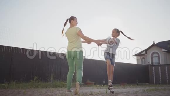 小可爱的女孩和她的母亲在后院里牵着手旋转女人和孩子玩得开心视频的预览图