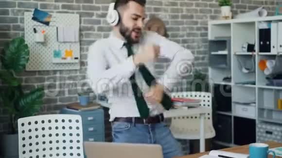 疯狂的上班族在工作中开心地跳舞听着耳机里的音乐视频的预览图