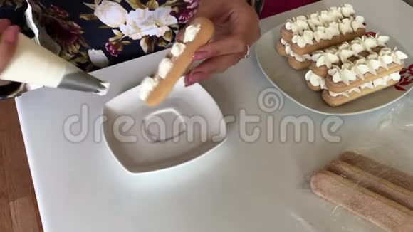 一个女人在萨沃亚迪饼干上涂上奶油她把它放在盘子里视频的预览图