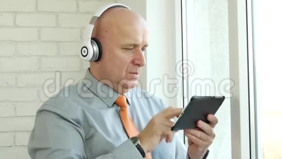 男士使用带蓝牙听音的电子平板和耳机视频的预览图