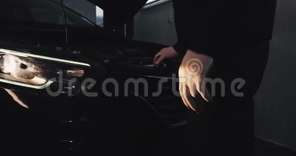 汽车修理厂的一名机械师戴着防护手套站在车上详细情况视频的预览图
