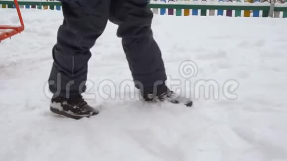在冬天散步的雪道上拖着雌性的腿穿着冬装和鞋子的少女的腿慢慢地走着视频的预览图