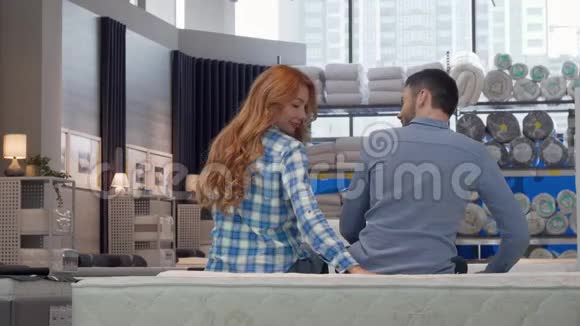 在家具店挑选新床的时候一对幸福的情侣对着镜头微笑视频的预览图
