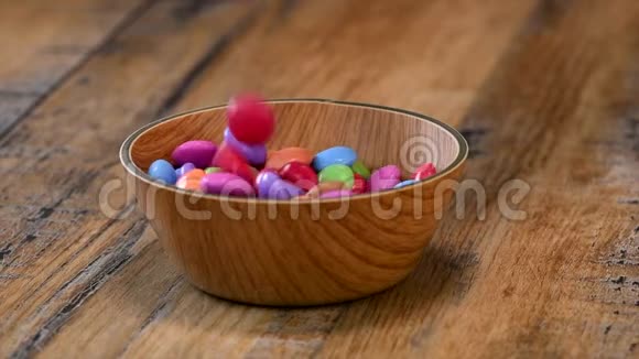 慢动作五颜六色的糖果放在木碗箱中孤立在木背景上视频的预览图