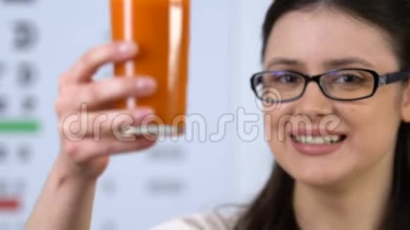 戴眼镜的微笑妇女身上有新鲜的胡萝卜汁维生素和眼睛健康视频的预览图