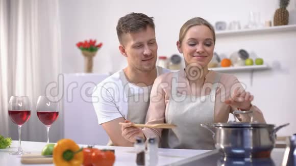 快乐夫妇一起在厨房做饭女性品尝汤健康食品视频的预览图