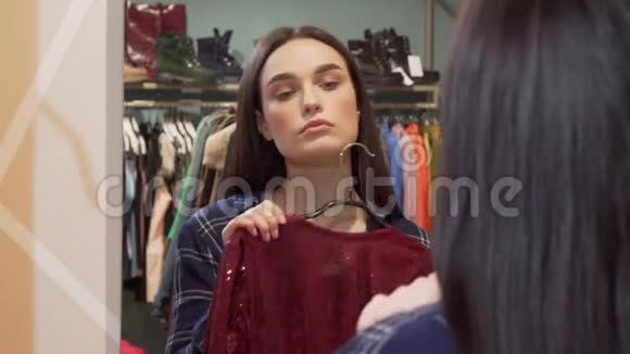 美丽的女人在两件衣服之间选择在服装店购物视频的预览图