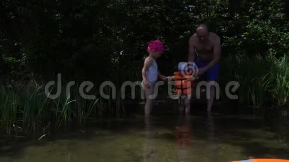 父女俩领着小儿子涉水穿救生衣的男孩视频的预览图