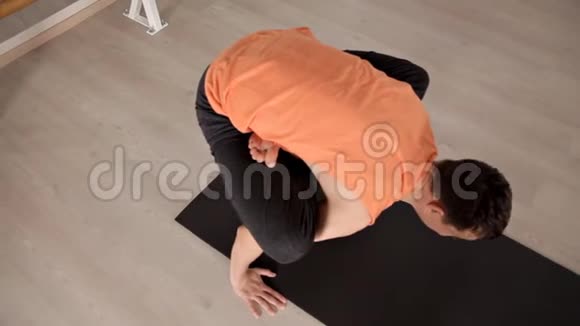 一个男人坐在瑜伽垫上在一个特殊的房间里做运动健康和力量的概念视频的预览图