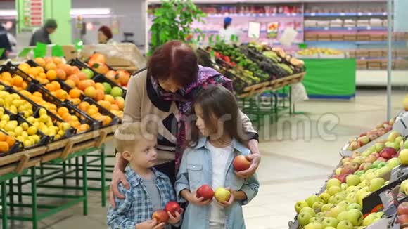 甜甜善良的奶奶带着小孩子在超市买新鲜的苹果视频的预览图