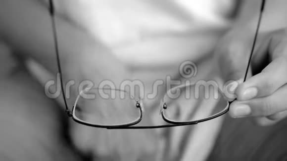 近镜头的男性手清洁黑色眼镜与他的白色t恤视频的预览图