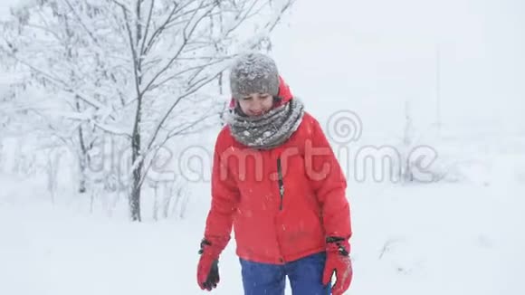 冬天的树林里一个穿着红色夹克的女人喜欢下雪扔雪视频的预览图
