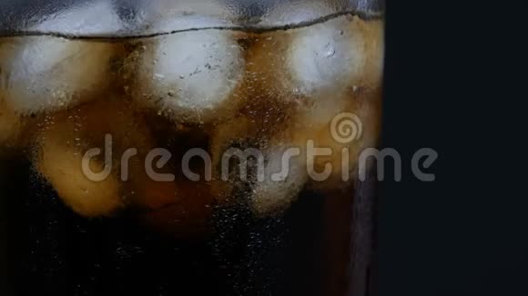 冰是混合在一个玻璃与气泡的冷可乐在一个透明的长玻璃与冰的黑色背景关闭视频的预览图