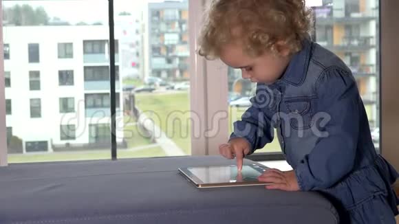可爱的小女孩在公寓院子里玩平板电脑视频的预览图