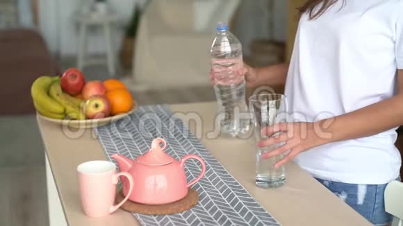 闭上女人的手打开瓶子把纯净水倒入桌子上的玻璃中慢动作视频的预览图