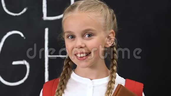 小女生对着镜头微笑黑板上写着字母教育视频的预览图
