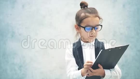 聪明的小女孩穿着商务服在此期间保存一个黑色文件夹把叶子举起来显示视频的预览图