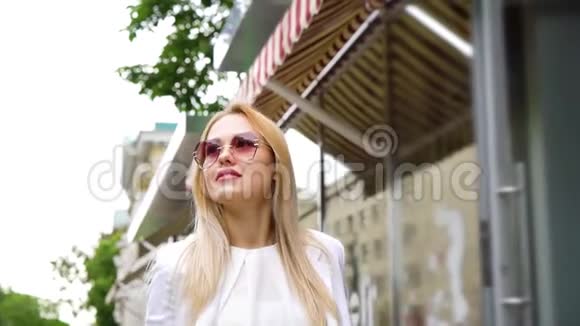 戴墨镜的金发美女在街上走着视频的预览图