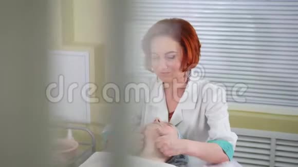 美容诊所面部按摩治疗女美容师轻轻按摩脸部和颈部两个微笑的女人视频的预览图