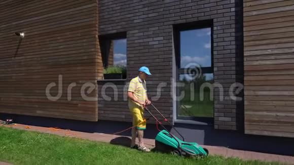 在房子附近用电动割草机割草园丁修剪草坪万向节视频的预览图