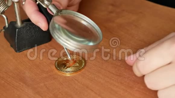 人用放大镜在桌子上制作假金比特币硬币的特写镜头4k视频视频的预览图