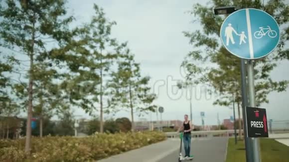 穿着黑色衣服和牛仔裤的男人骑着电动滑板车在城市里转悠视频的预览图