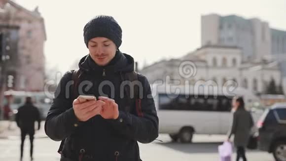 男人用智能手机在城市街道上行走视频的预览图
