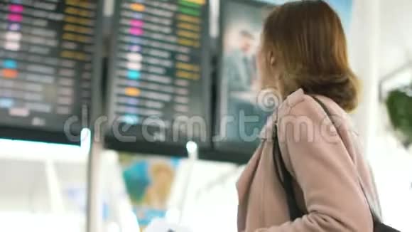 女孩用航班时刻表检查她的机票在航班时刻表前一位女士的肖像视频的预览图
