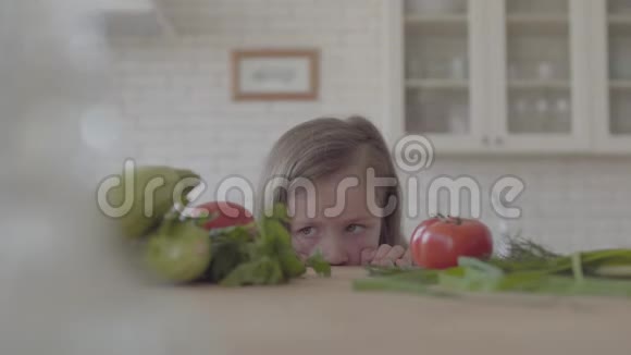 美丽的小女孩看着桌子上有西红柿葫芦丝青菜洋葱孩子吃了番茄就跑视频的预览图
