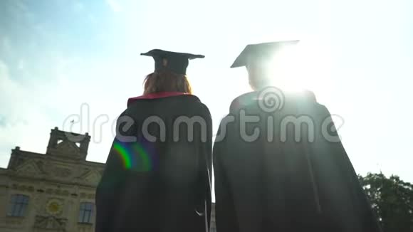 后景两名学生在壁炉前庆祝他们的毕业在大学大楼前毕业新生活视频的预览图