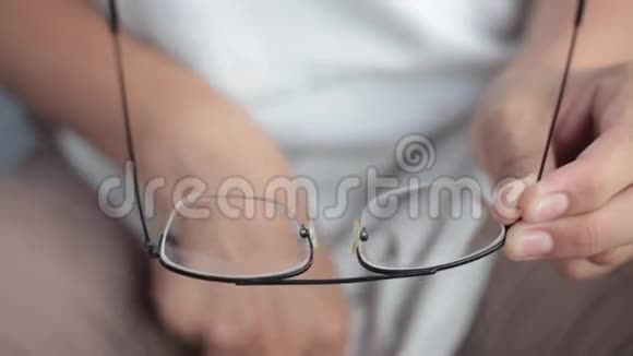 近镜头的男性手清洁黑色眼镜与他的白色t恤视频的预览图