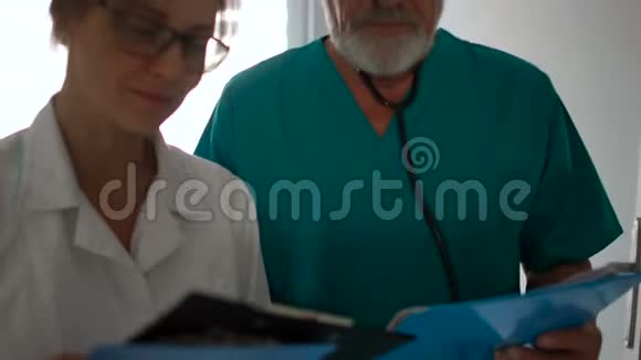 女医生和一名男助理正沿着大厅走去预约医务人员在诊所工作视频的预览图