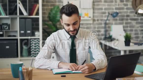 坐在办公室桌上的一个用笔记本电脑打字的大胡子视频的预览图